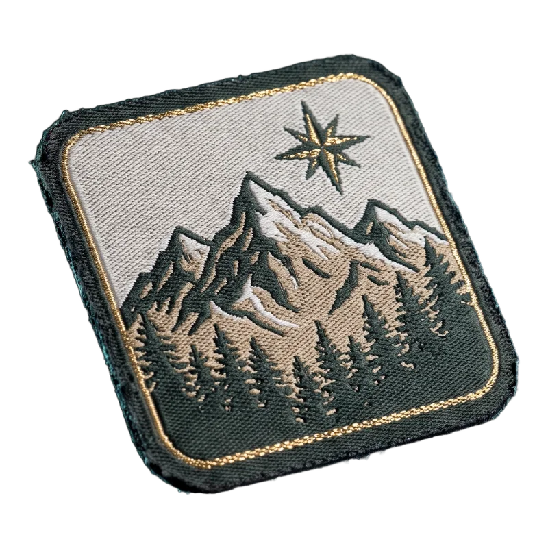 Gewebter Patch mit fein gewebter Berglandschaft und Kompassstern